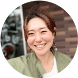 卒業生の女性が笑顔でこちらを向いている様子